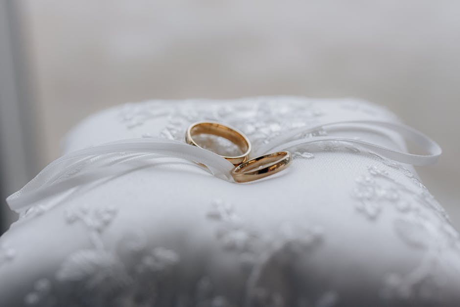 Wedding ring bearer pillow with lace and pearl detail and rings tied with ribbon