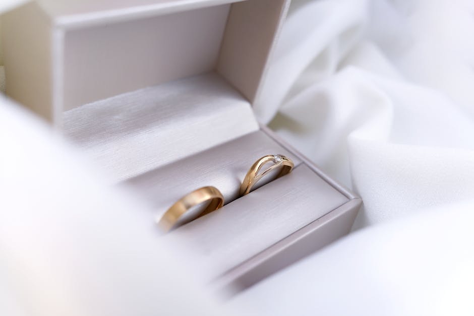Sage green velvet wedding ring box with two gold bands inside, a popular 2026 wedding ring box idea