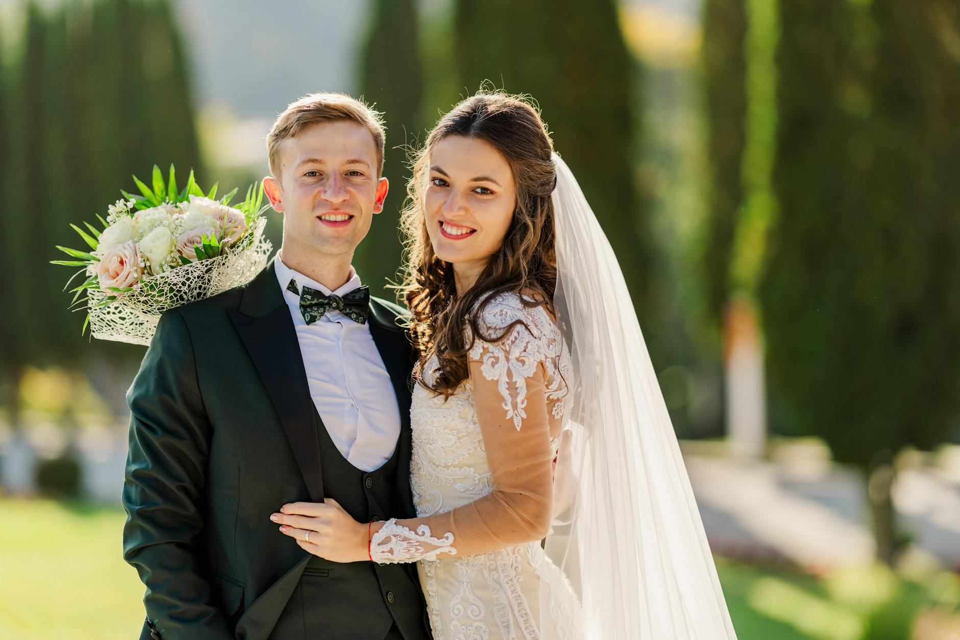 Wedding photo booth backdrop ideas featuring a dense greenery wall with white florals