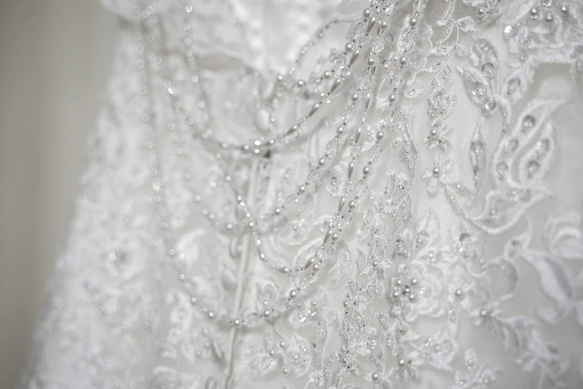 Decorative wedding hanger trimmed with pearls and crystals beside a lace gown