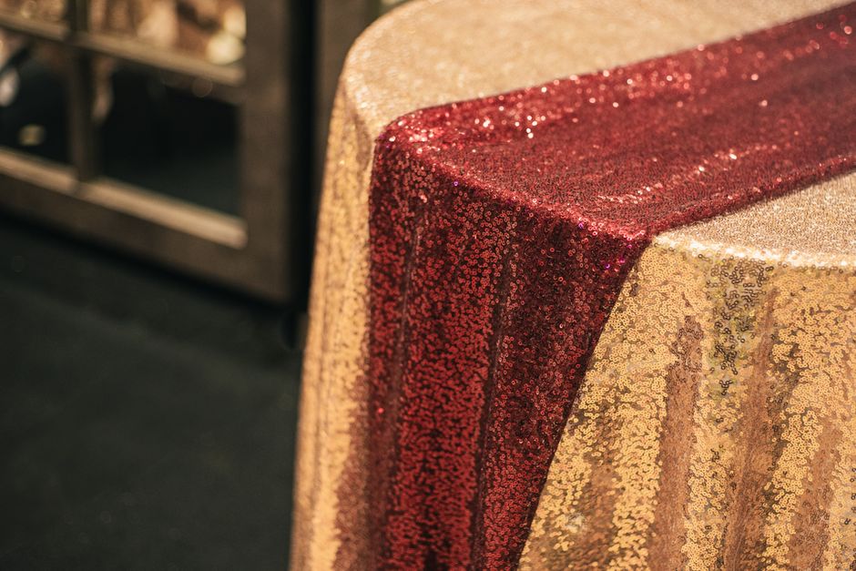 Gold sequin wedding table runner catching candlelight