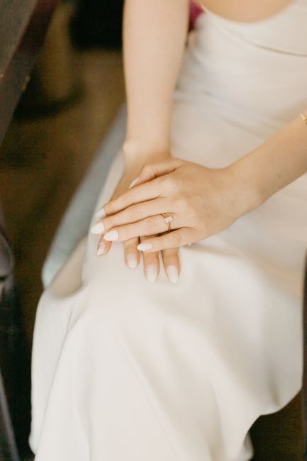 Close-up of a French tip bridal manicure with an engagement ring