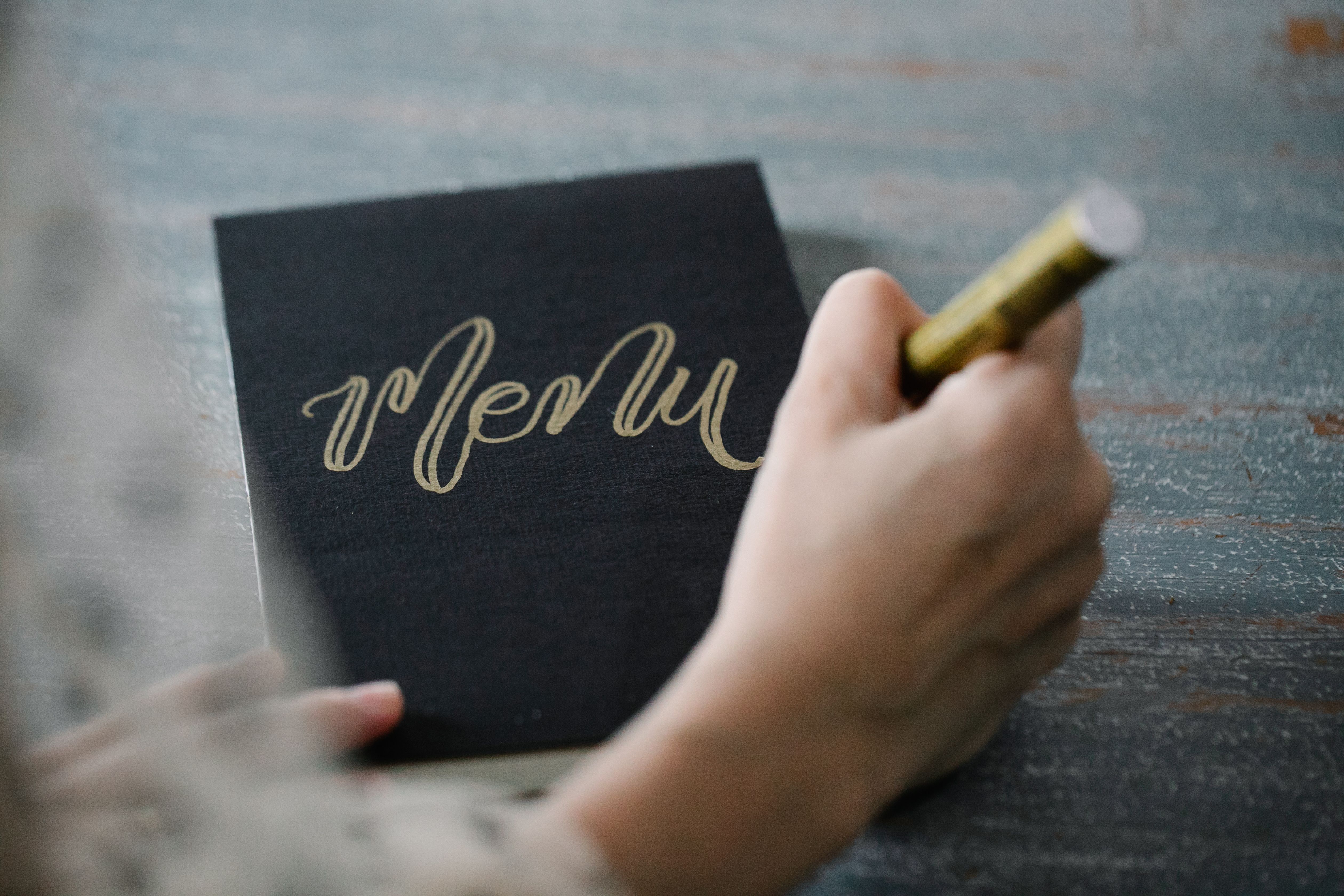 Elegant wedding menu card with calligraphy lettering and a gold foil border, showing a formal wedding menu card design idea