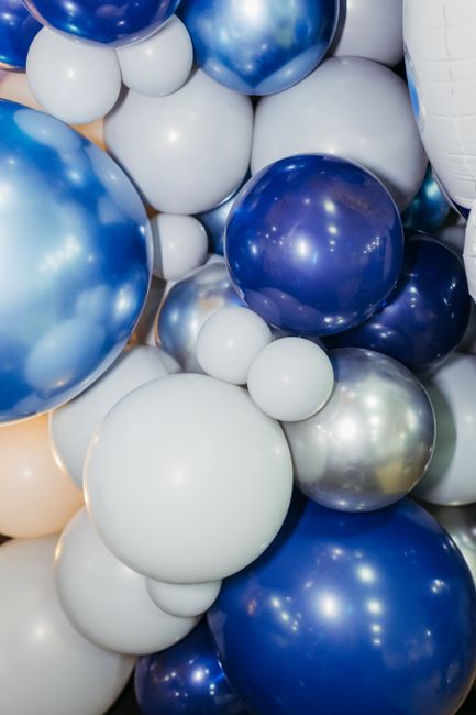 Organic balloon garland draped over a wedding arbor structure