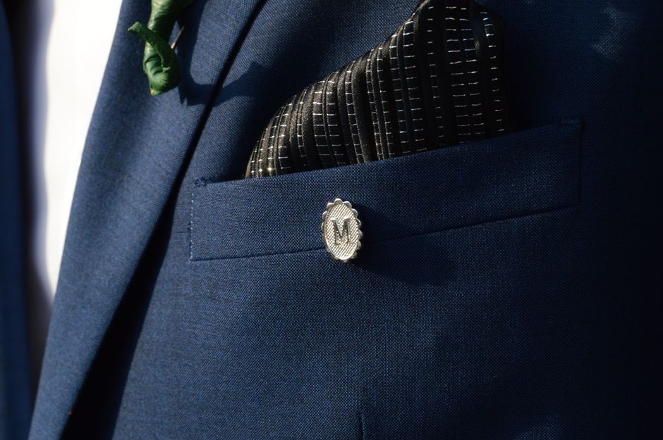 Close-up of a navy suit jacket pocket with a gold satin pocket square, showing color pairing for wedding attire