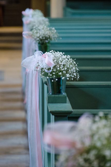 White satin pew bows hanging on church pews for a wedding ceremony