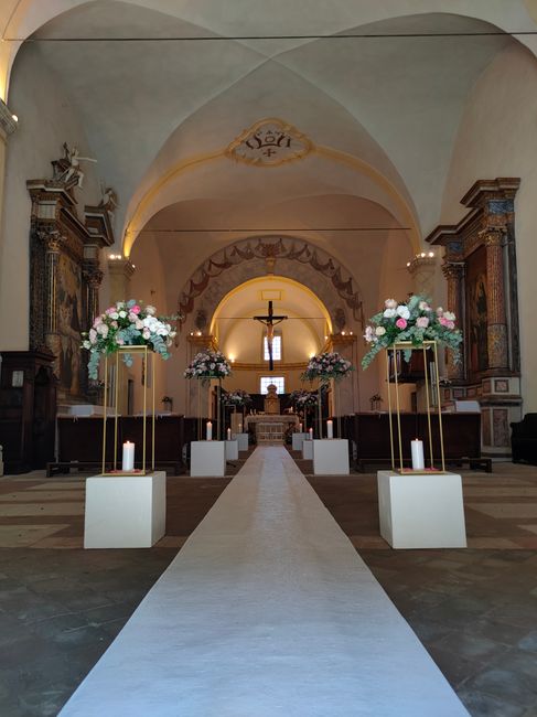Free-standing floral aisle decorations beside church pews