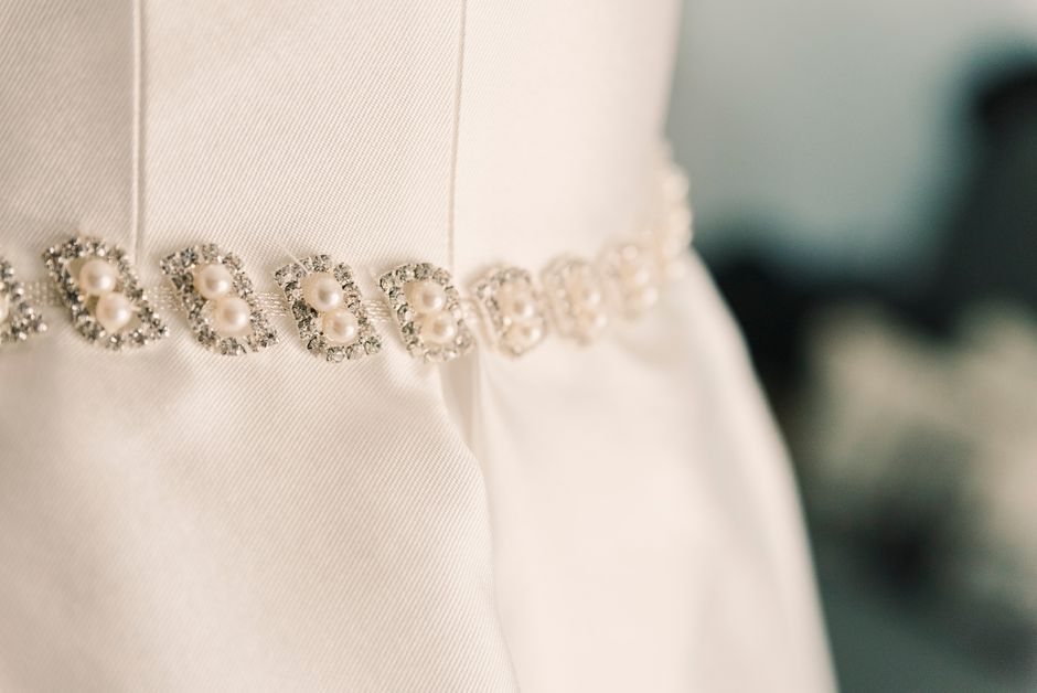 Pearl and crystal wedding dress sash in gold on an ivory gown