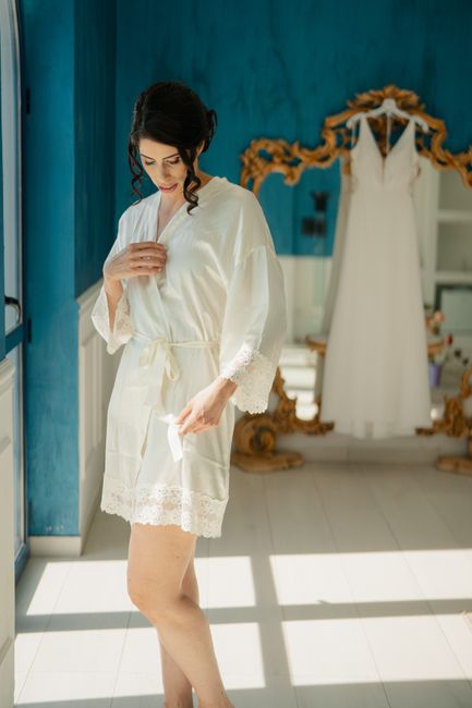 Bride in a soft robe holding a white lace babydoll for her honeymoon