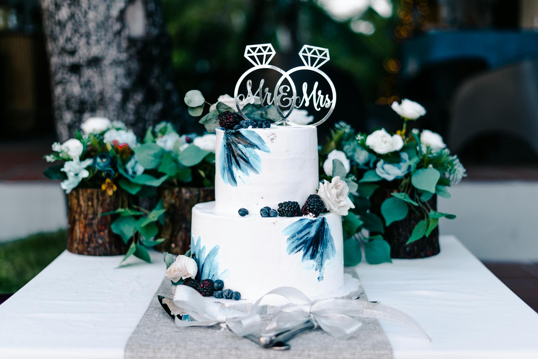 Rustic wood Mr and Mrs wedding cake topper on a naked cake with greenery
